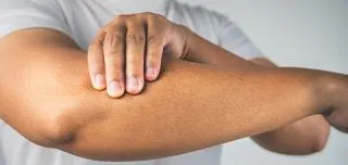 Person holding elbow due to cubital tunnel syndrome caused by ulnar nerve entrapment
