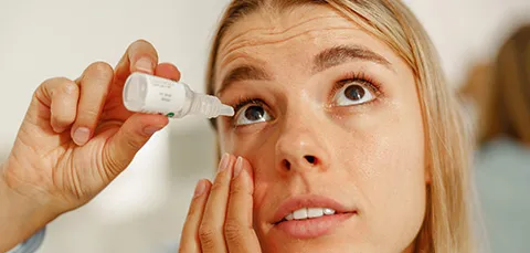 Pregnant woman applying eye drops to relieve dryness, illustrating common dry eye symptoms during pregnancy.  