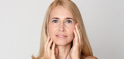 Middle-aged woman touching her rejuvenated face after endoscopic facelift in Turkey