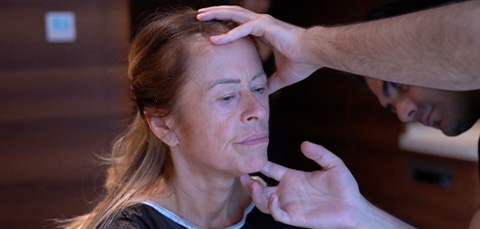 Surgeon examining middle-aged womans face before facial aesthetic procedure