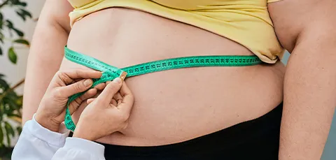 A doctor measures a patients waist with a tape measure before gastric band surgery to show weight loss progress