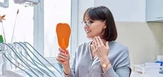 happy dental patient looking her teeth on mirror