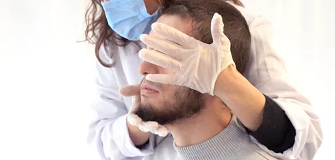 Man in Turkey during pre-op exam for jaw surgery, doctor assessing jaw alignment and facial structure before procedure.