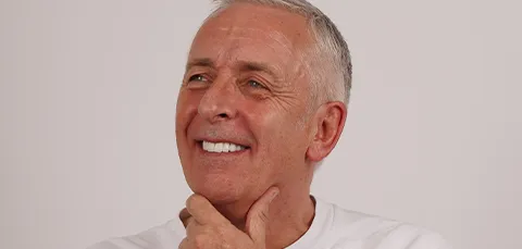 Older man smiling confidently after dental implant treatment, showing natural-looking teeth
