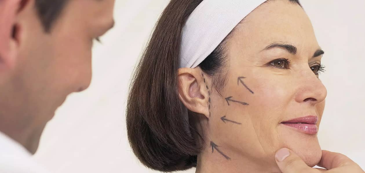 middle-aged woman with lines on her face examined by doctor for facelift