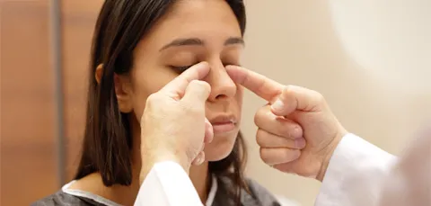 Doctor examining woman’s nose before rhinoplasty in Turkey, assessing nasal structure for cosmetic surgery.