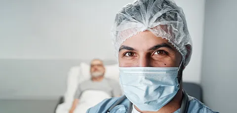Surgeon wearing a mask with a patient in the background, representing the surgical team for a tummy tuck procedure