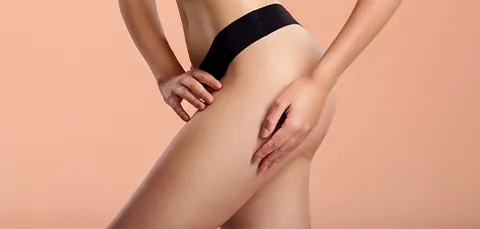 Woman highlights her posterior thigh area, demonstrating the target for a posterior thigh lift procedure